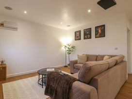 A living room with a brown sofa coffee table floor lamp and three animal portraits on the wall at Hub House in Three Oaks near Hastings