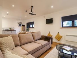 A living room with a beige sofa a glass coffee table and a wall mounted tv at Hub House in Three Oaks near Hastings