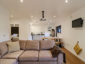 A living area with a beige sofa in front of a dining table and kitchen at Hub House in Three Oaks near Hastings