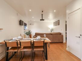 A dining area with a wooden table set for four and a brown sofa in the living room at Hub House in Three Oaks near Hastings