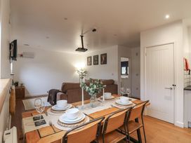 A dining table set with plates bowls glasses and candles next to a living room with brown sofas and animal pictures on the wall at Hub House in Three Oaks near Hastings