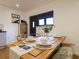 A dining area with a wooden table set with plates bowls wine glasses and a vase with greenery at Hub House in Three Oaks near Hastings