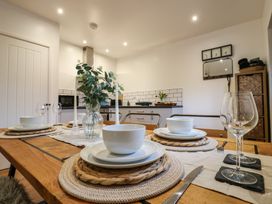 A dining table set with white bowls plates glasses and candlesticks in a kitchen with white walls and cabinets at Hub House in Three Oaks near Hastings