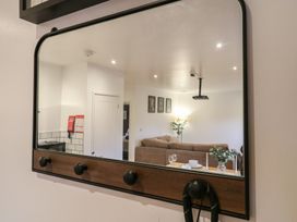 A wall mirror reflecting a living room with a brown sofa a dining table set with plates glasses and a vase with flowers at Hub House in Three Oaks near Hastings