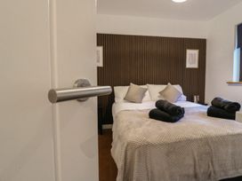 A bedroom with a bed covered in beige blanket and black towels on top at Hub House in Three Oaks near Hastings