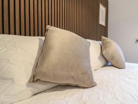 A bed with two beige pillows and white bedding against a brown slatted wall at Hub House in Three Oaks near Hastings