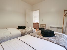 A bedroom with two single beds with folded towels on them a chair and a clothes rack at Hub House in Three Oaks near Hastings