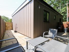 An outdoor area with chairs and a table beside a shed at Hub House Three Oaks near Hastings