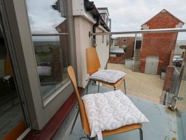 A balcony with wooden chairs and cushions at Coastguard Lookout in Wyke Regis