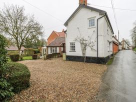 A house with a gravel driveway and trees at White Gates in Banham