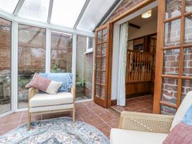 A conservatory with an armchair and rug at White Gates in Banham