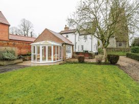A garden with a conservatory and a house at White Gates in Banham