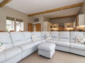 A living room with a sectional sofa and kitchen area at The Gatehouse 