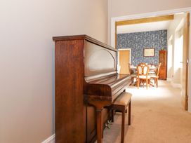 A piano and wooden stool in a dining room at The Gatehouse