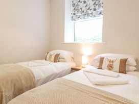 A bedroom with two beds, a lamp, and a window at The Gatehouse in 