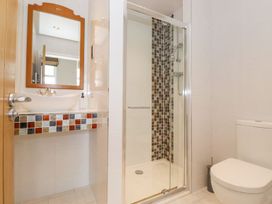 A bathroom with a sink, mirror, shower, and toilet at The Gatehouse 