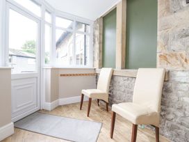 A conservatory with two chairs and a stone wall at The Gatehouse