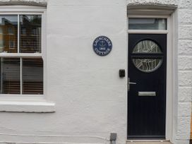 A white wall with a window and a blue door with circular glass at Launcher's Cottage in Scarborough