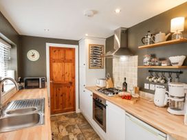 A kitchen with wooden countertops a wooden door and shelves with kitchenware at Launcher's Cottage in Scarborough