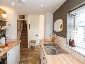A kitchen with wooden countertops a double sink a window with blinds stairs and chairs near a small door at Launcher's Cottage in Scarborough