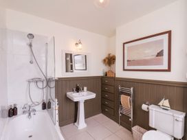 A bathroom with a bathtub shower combination pedestal sink mirror cabinet toilet and towel rack at Launchers Cottage in Scarborough