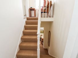 A staircase with beige carpet leading to an upper floor with a wooden chair and small table at Launcher's Cottage in Scarborough