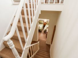 A staircase with beige carpet leading down to a bedroom with two single beds and a lamp at Launcher's Cottage in Scarborough