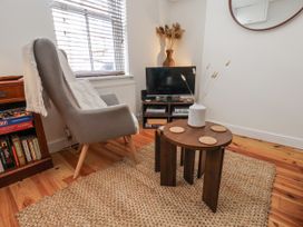 A living room with an armchair, television, and coffee table at Launcher's Cottage in Scarborough