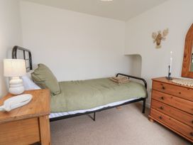 A bedroom with a bed, lamp, dresser and towels at Launcher's Cottage in Scarborough
