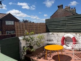 A garden with a yellow table and white chairs at Launcher's Cottage in Scarborough