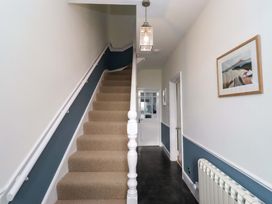 A hallway with a staircase and light fixture at Dinguardi in Seahouses