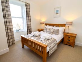 A bedroom with a bed and nightstands at Dinguardi in Seahouses