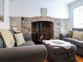 A living room with two grey sofas and a stone fireplace with a wood-burning stove at Cartref in Llangernyw