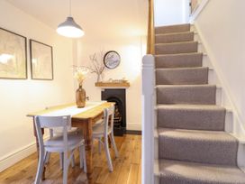 A dining area with wooden table and chairs next to carpeted stairs at Cartref in Llangernyw