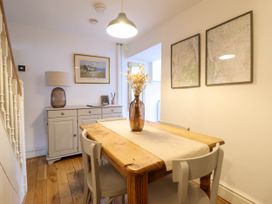 A dining room with wooden table and chairs and a sideboard under a staircase at Cartref in Llangernyw