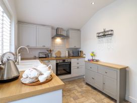 A kitchen with grey cabinets wooden countertops a kettle and tea set on the counter and an oven with a microwave at Cartref in Llangernyw