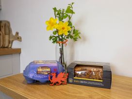 A kitchen counter with a carton of eggs a box of Bara Brith cake a red dragon decoration and a vase with daffodils at Cartref in Llangernyw