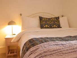 A bedroom with a bed a nightstand and a lamp at Cartref in Llangernyw