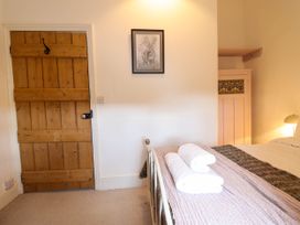 A bedroom with a wooden door a bed with towels and a framed picture on the wall at Cartref in Llangernyw
