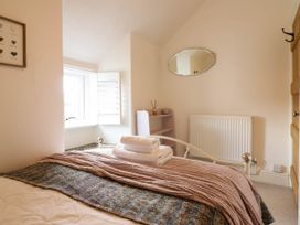 A bedroom with a bed folded towels a small shelf mirror radiator and window at Cartref in Llangernyw