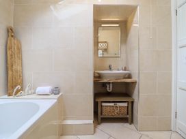 A bathroom with a bathtub and a washbasin with mirror at Cartref in Llangernyw