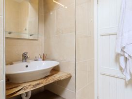 A bathroom sink with a wooden countertop mirror and towel on the door at Cartref in Llangernyw