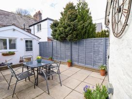 A patio with a table and four chairs surrounded by potted plants and a fence at Cartref in Llangernyw