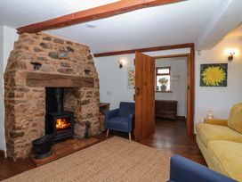 A living room with a fireplace and blue chairs at 1 Eastdon Cottages in Exeter