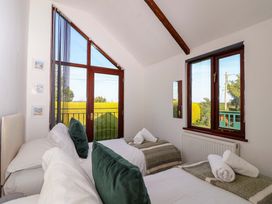 A bedroom with two beds and windows showing green fields at 1 Eastdon Cottages in Exeter