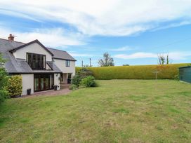 A garden with a house and hedge at 1 Eastdon Cottages in Exeter