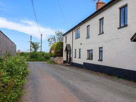 A building along a road with trees and signs at 1 Eastdon Cottages in Exeter