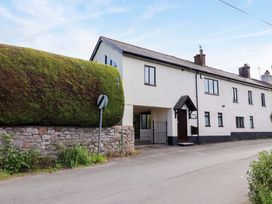 A house with a large bush and stone wall at 1 Eastdon Cottages Exeter