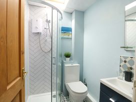 A bathroom featuring a shower, toilet, and sink at Riverbank Cottage in Beddgelert