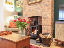 A living room with a fireplace and flowers on a table at Derwen House Llangollen
